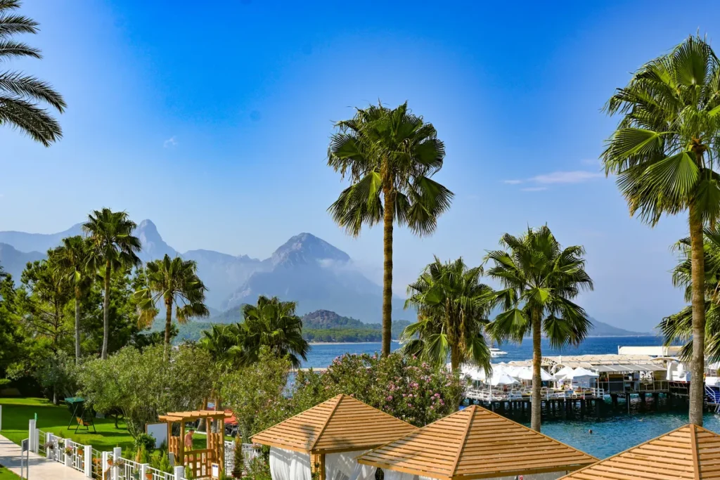 A view on the coastline of Antalya, Turkey, with housed in the foreground, palms in the middle ground and mountain in the background.