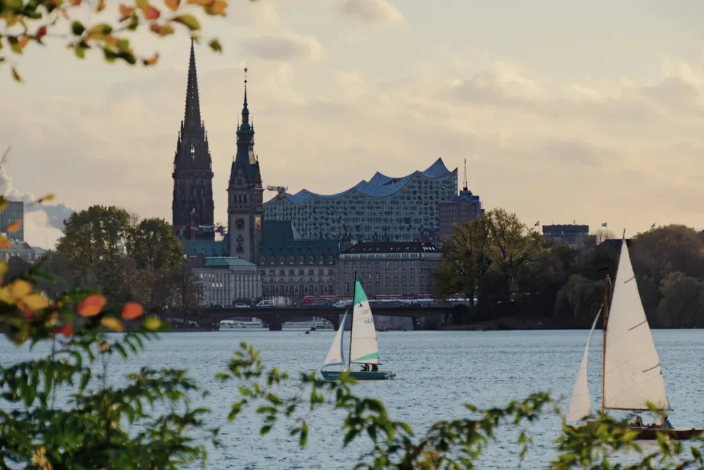 A view of the Alster River in Hamburg, with sailboats in the foreground and churches in the background. The image serves as a representative photo for a running route in Hamburg for aircrews on layover.