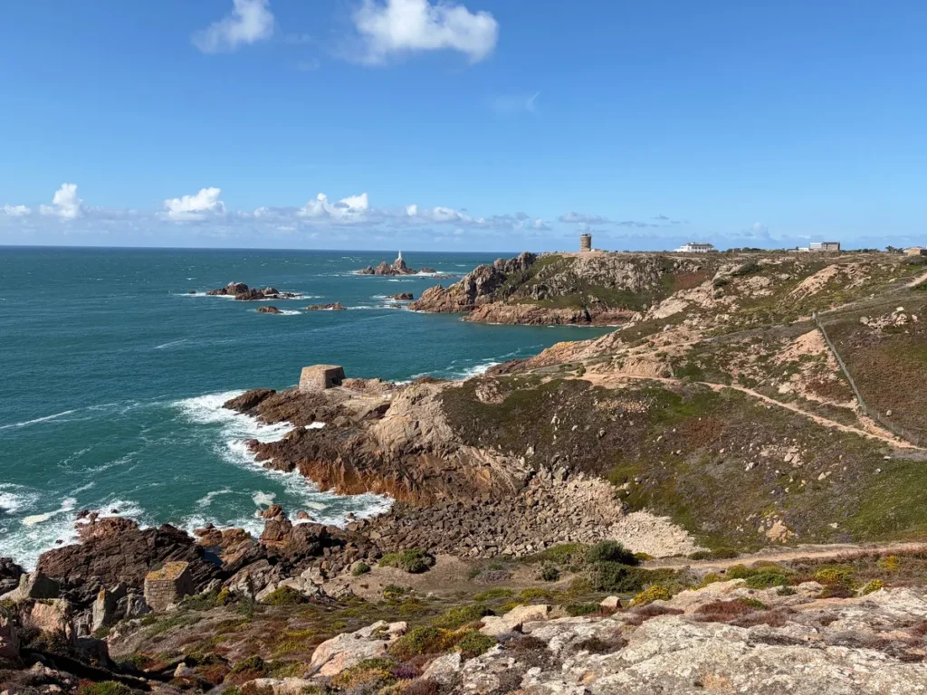 The southwest coast of Jersey. In the foreground is the coastal trail, in the background a white lighthouse. The photo serves as a symbol of a running route in Jersey.